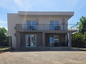 A two-story building with a balcony, a covered outdoor seating area, and a paved patio. - Villa Magnolia Pirovac (Pirovac)