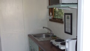 A compact kitchen with a sink, microwave, toaster, and a green towel hanging on the door. - Quiet retreat in rural Cornish garden. (Truro)