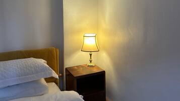 Habitación de hotel con una cama, una mesita de noche con lámpara y una lámpara de pared.