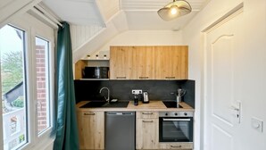 A compact kitchen with wooden cabinets, a dishwasher, a sink, and an oven. - Studio Horizon Bleu (5-minute walk from the sea) (Criel-sur-Mer)