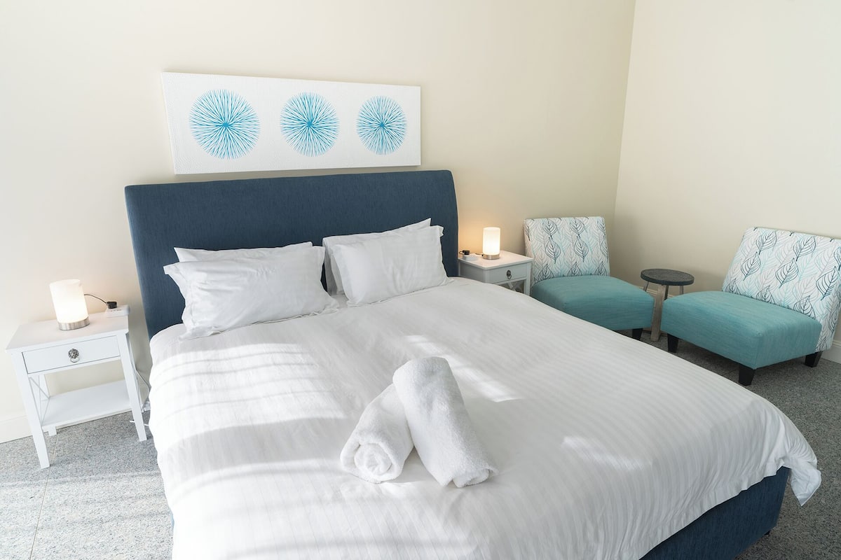 A hotel room with a large bed, two bedside tables, a small table, and two chairs.