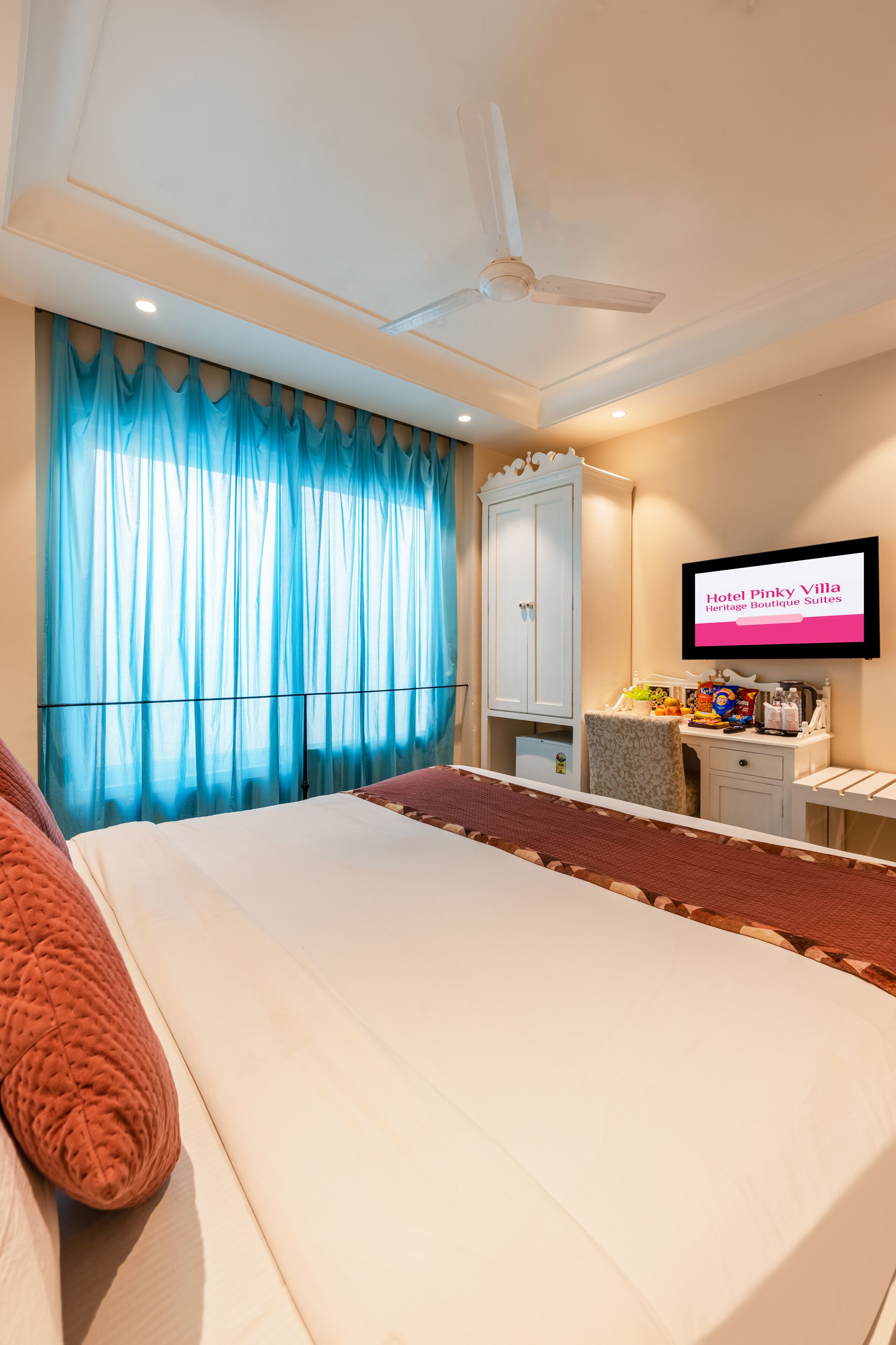 Een hotelkamer met een bed, een plafondventilator, een televisie en een kledingkast.
