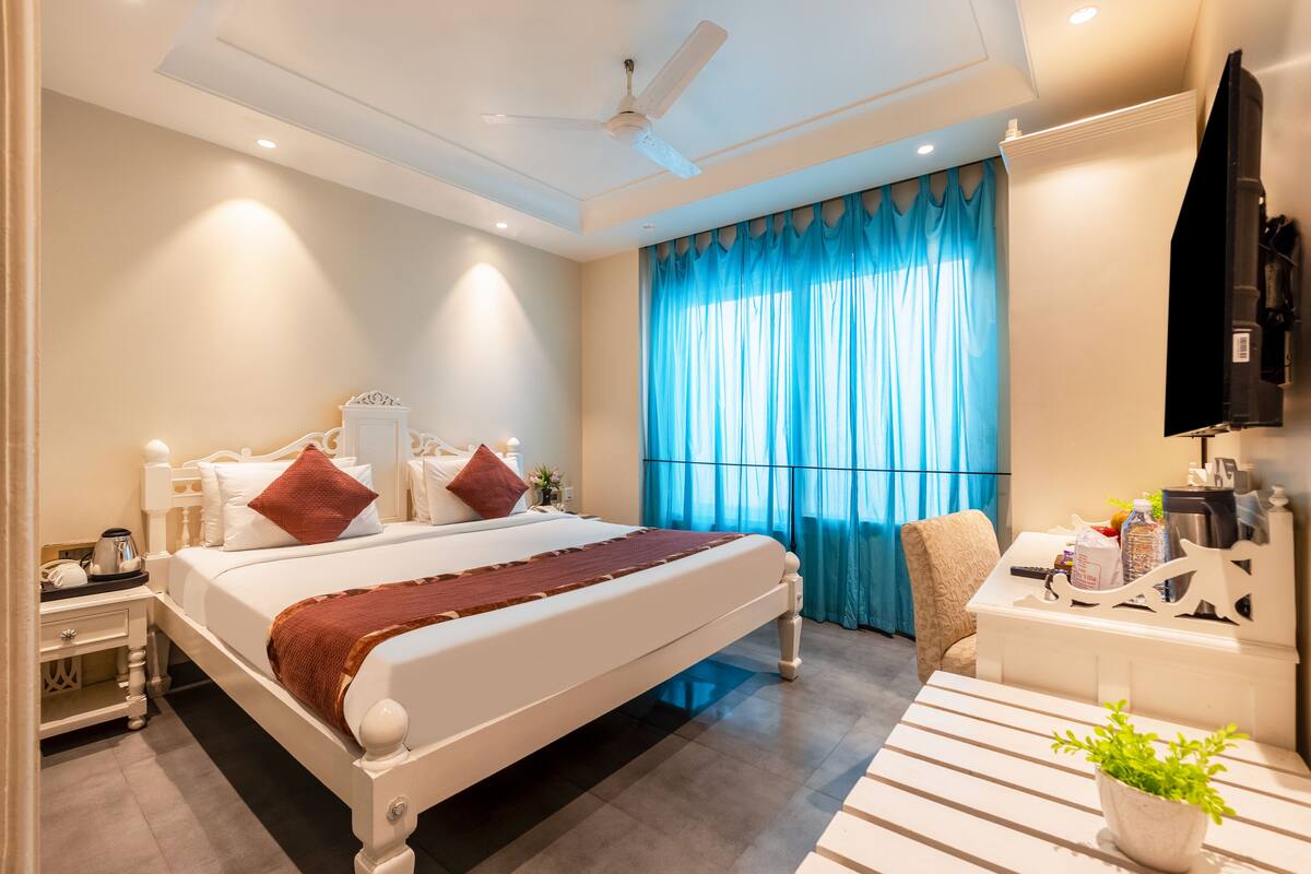 A modern hotel bedroom with a large bed, bedside tables, a desk, and a chair.