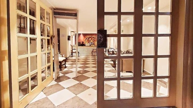 A hotel lobby with a checkered floor, a large wooden door with glass panels, and a seating area with tables and chairs. - The Pinky Villa Heritage Boutique Suites (New Delhi)