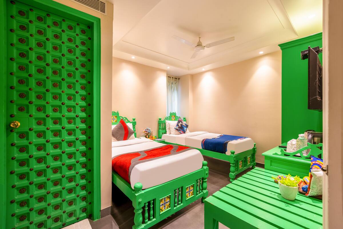 A room with two beds, a green door, and a green table with snacks.