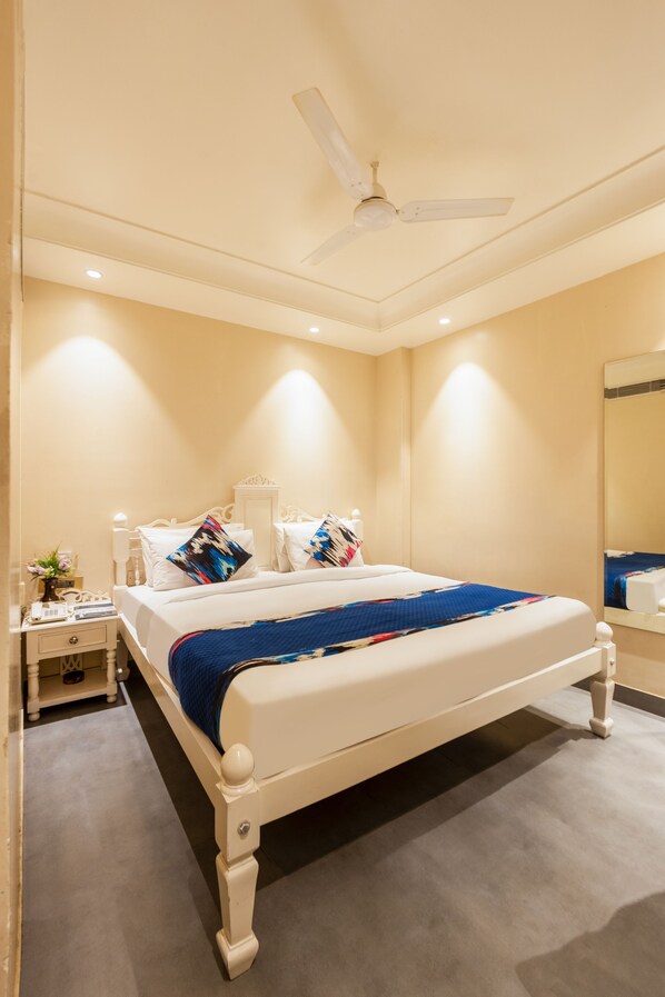 A bedroom with a bed, nightstands, a ceiling fan, and a mirror.