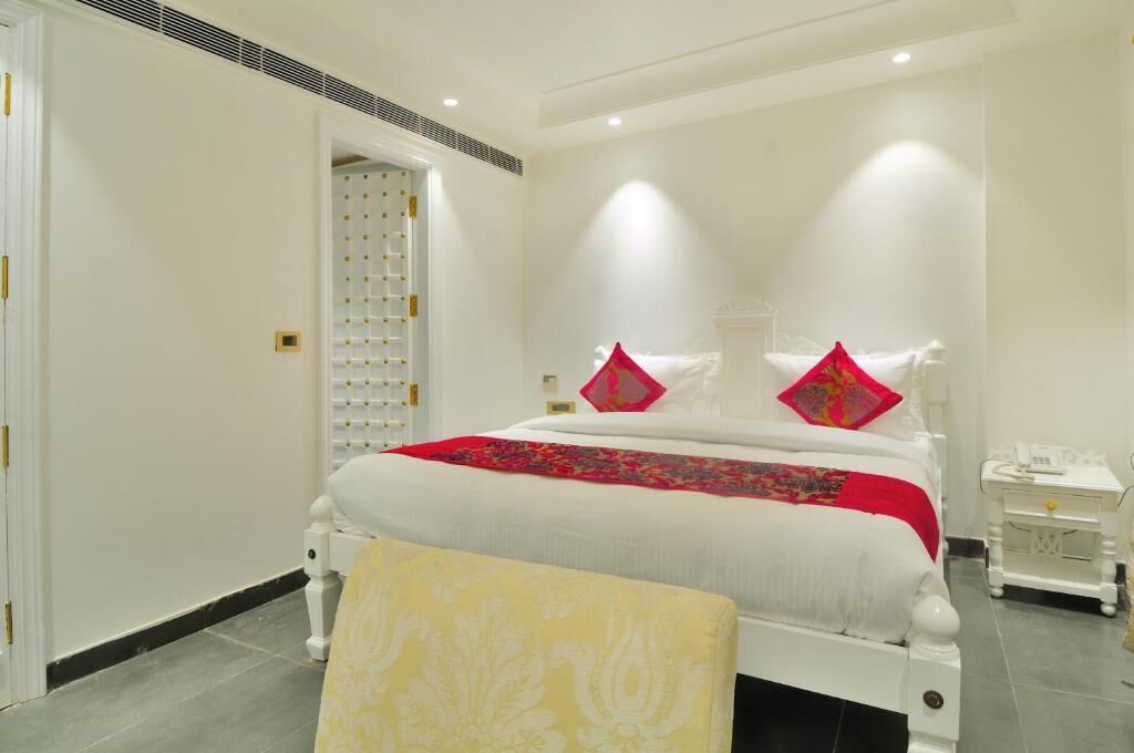 A hotel room with a large bed, a bedside table, a nightstand, and a chair.