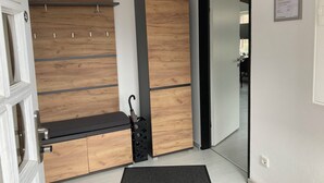 A modern room with a wooden wardrobe, a bench, and a door leading to another area. - Work & Relax - Your workation / vacation apartment on the North Sea with stable WLAN (Eddelak)