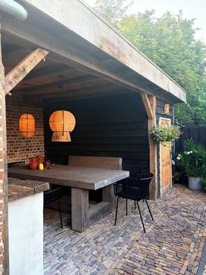 An outdoor patio with a wooden table and chairs, a brick floor, and hanging paper lanterns. - Vacation home * Atmospheric * Luxury * - 3 spacious bedrooms, each with private bathroom (Nuth)