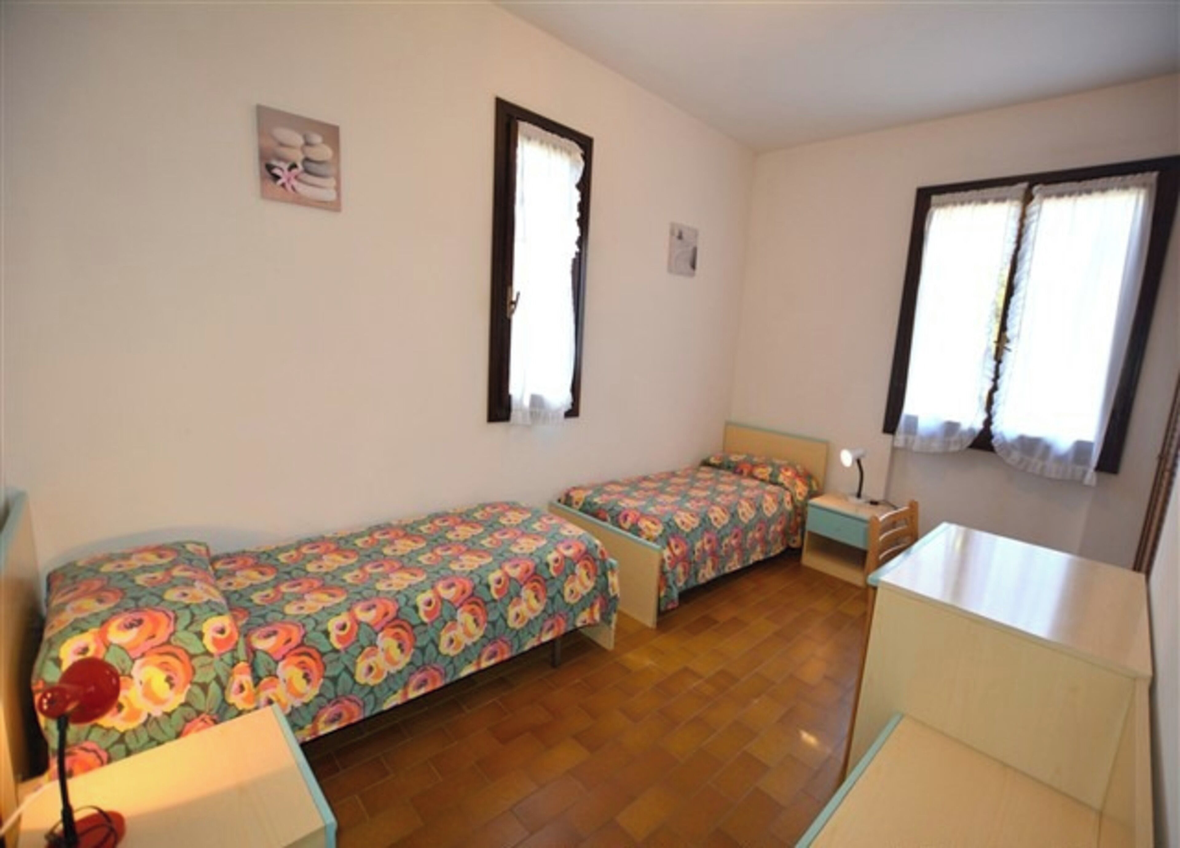 A room with two single beds, a small desk, and a chair.