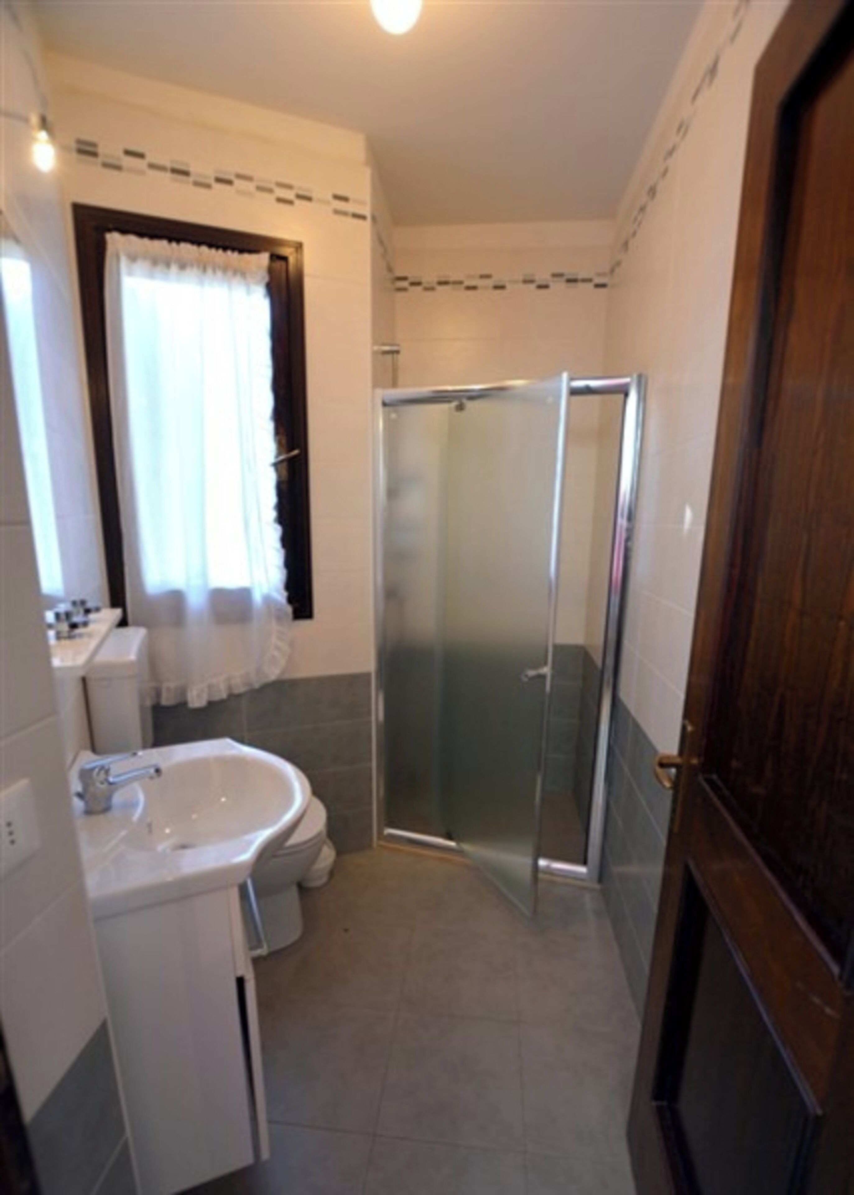 A bathroom with a glass shower enclosure, a sink, and a toilet.