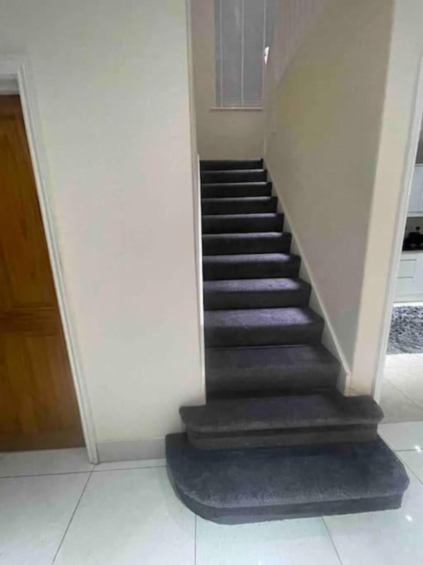 Una escalera con barandilla y rellano alfombrados.