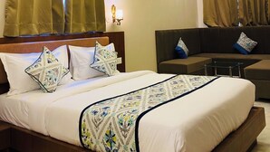 Een hotelkamer met een groot bed, een slaapbank, een plafondventilator en een kroonluchter.