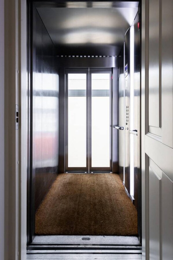 Un ascensor con piso alfombrado y paredes metálicas.