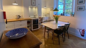 Una cocina moderna con armarios blancos, encimera de madera, estufa y comedor con mesa y sillas.
