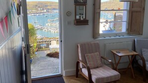 Una habitación con vista a un puerto deportivo, una silla de madera, una mesita y un radiador.