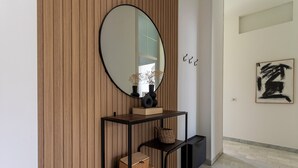 A modern interior with a wooden panel wall, a black metal console table with decorative items, and a framed abstract painting on the wall.