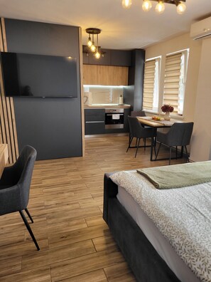 A modern, compact living space with a kitchenette, dining area, and a bed. - Stella Cozy Apartament (Targu Mures)