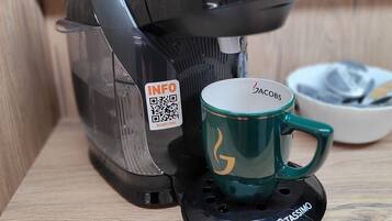 A coffee maker with a QR code and a green mug on a wooden surface.