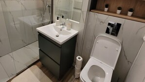 Moderni kylpyhuone, jossa on suihku, wc ja pesuallas.