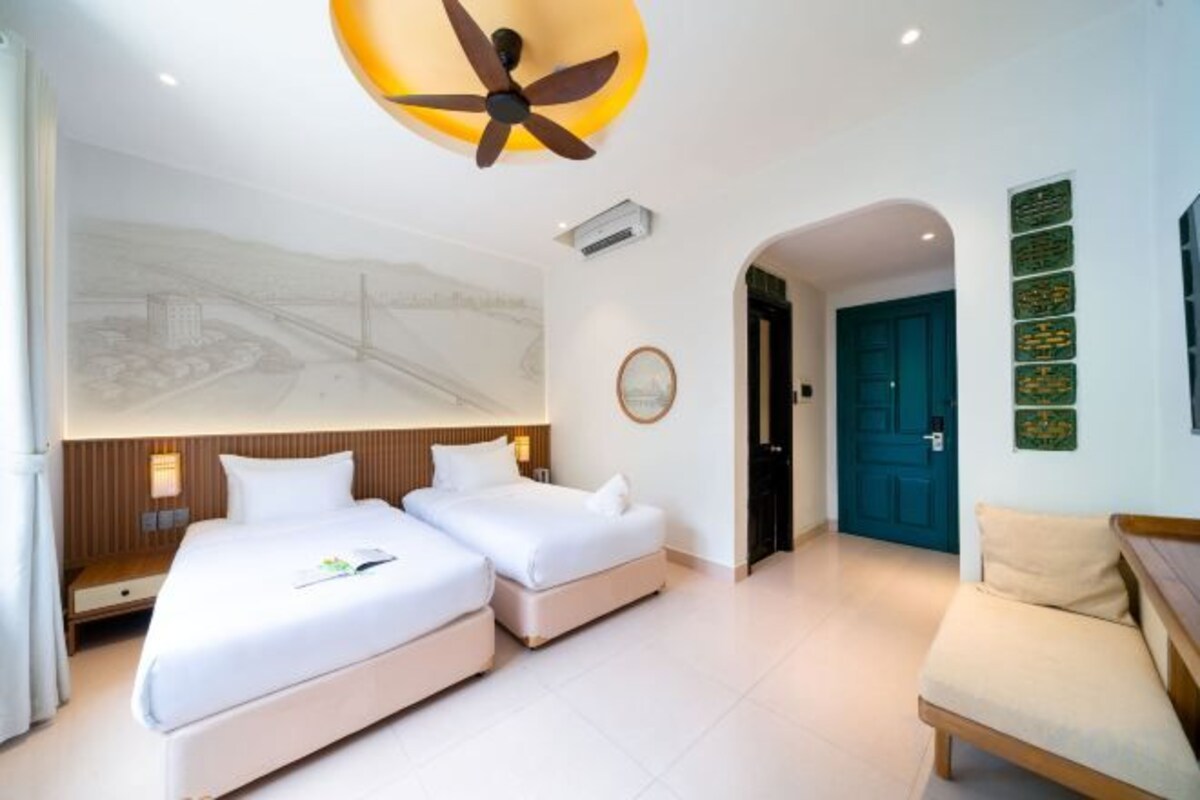 A hotel room with two beds, a ceiling fan, a large window, and a door leading to another room.