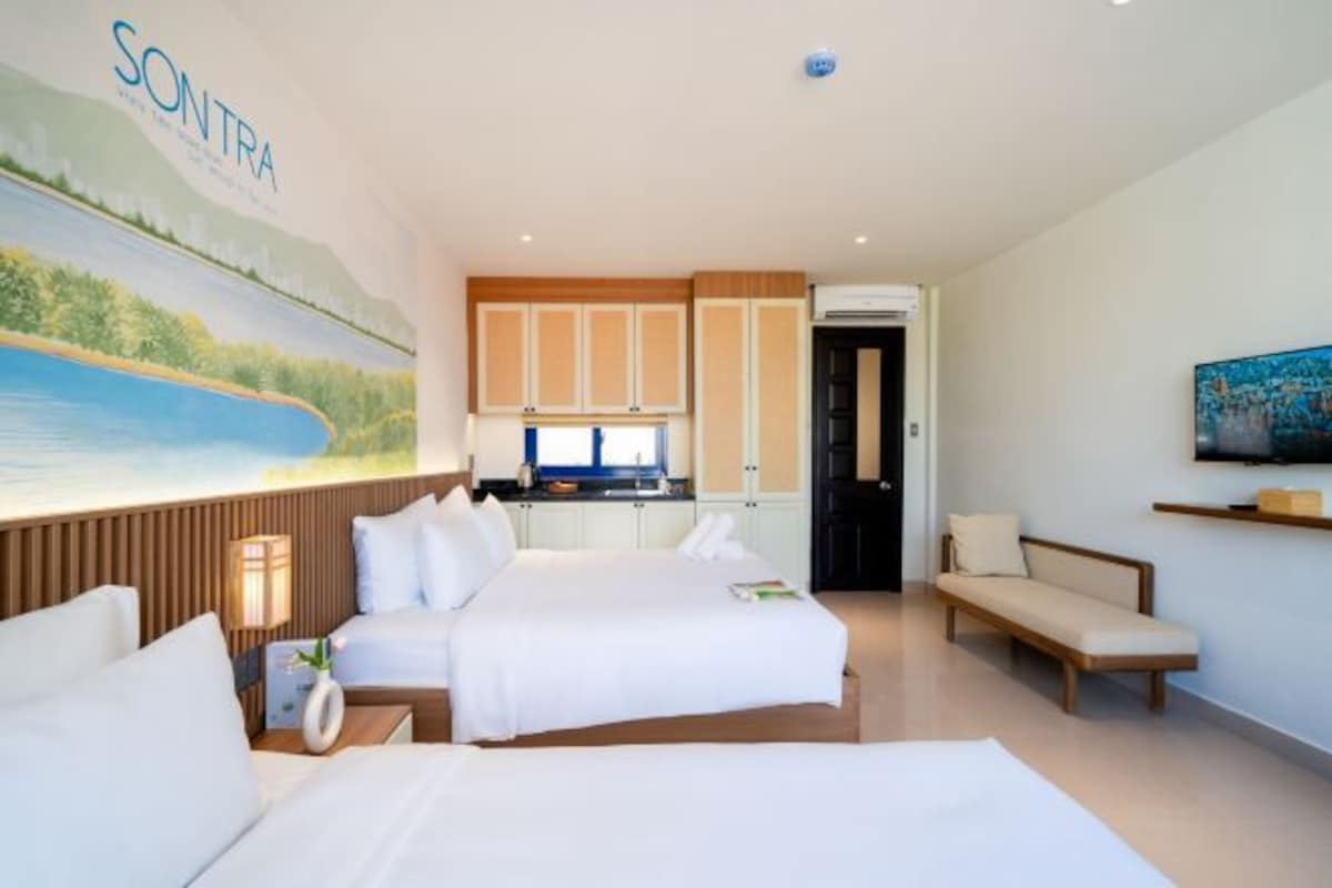 Een hotelkamer met een bed, een slaapbank, een televisie, een schilderij en een kitchenette.