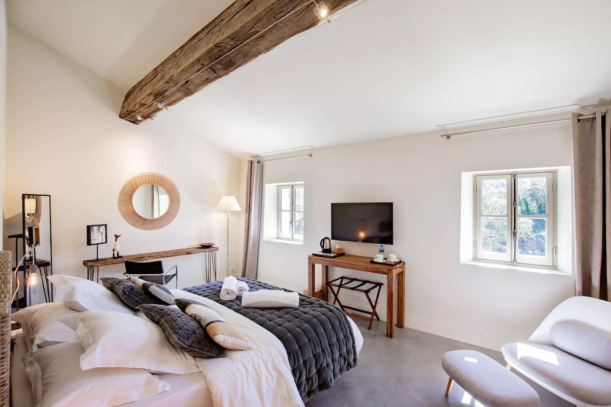 Een ruime slaapkamer met een groot bed, een bureau, een televisie en uitzicht op de omgeving.