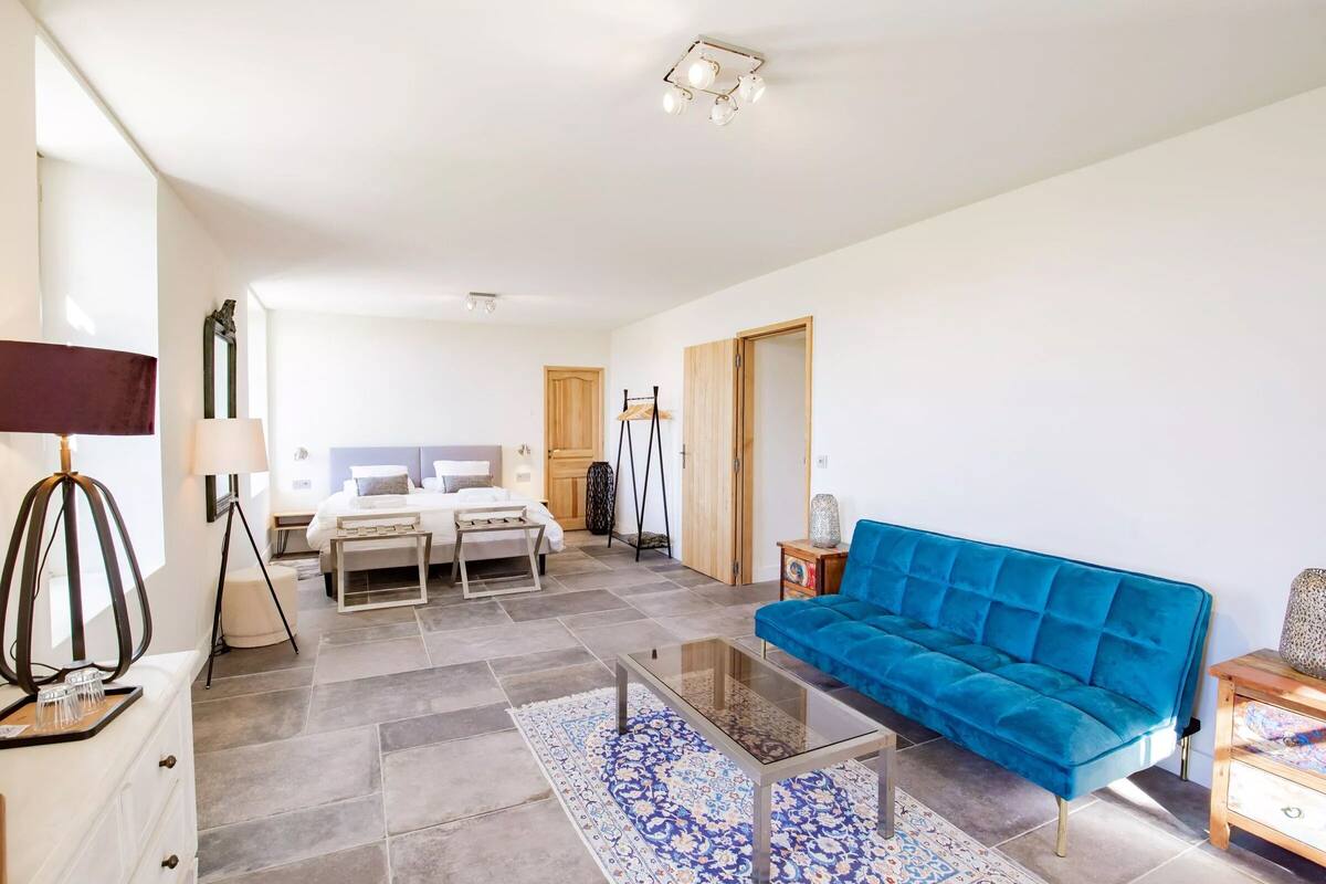 Een moderne woonkamer met een blauwe bank, een glazen salontafel en een kamerkleed met dessin.