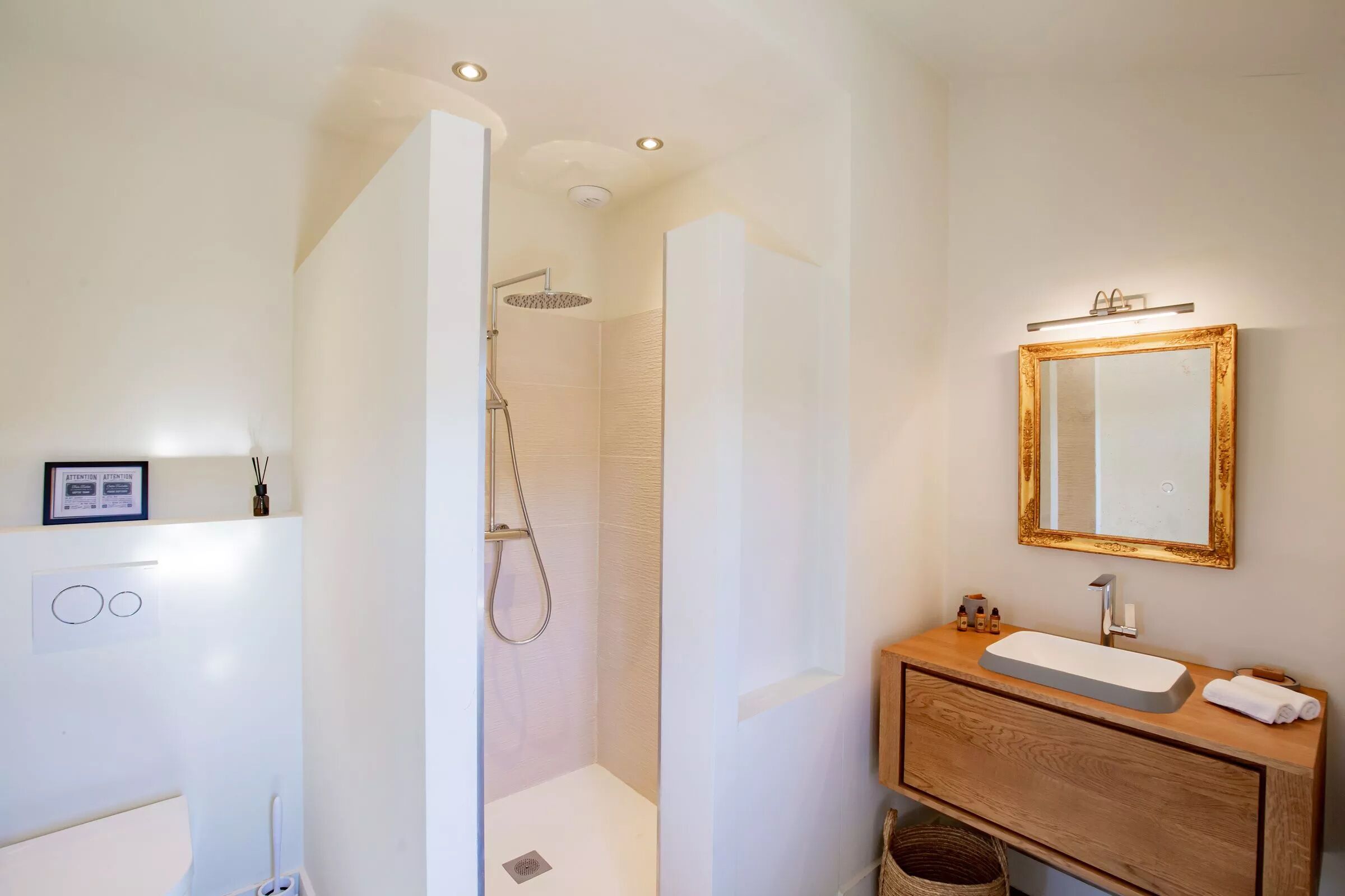 Ein Badezimmer mit Dusche, Waschbecken, Spiegel und einem gerahmten Bild an der Wand.