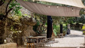 An outdoor patio with a table and chairs, a canopy, and a rustic stone wall. - Château les Gardis (Lourmarin)