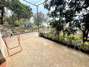 A patio area with tiled flooring, a clothes drying rack, potted plants, and a stone wall. - Apartment Niro 2 (Dramalj)