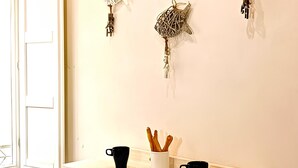 A kitchen with a wooden countertop, a bar stool, and three wall-mounted decorative items. - Summer House (Trapani)