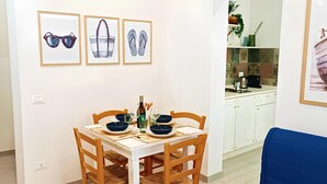 A dining area with a white table set for four, wooden chairs, and framed artwork on the wall. - Summer House (Trapani)