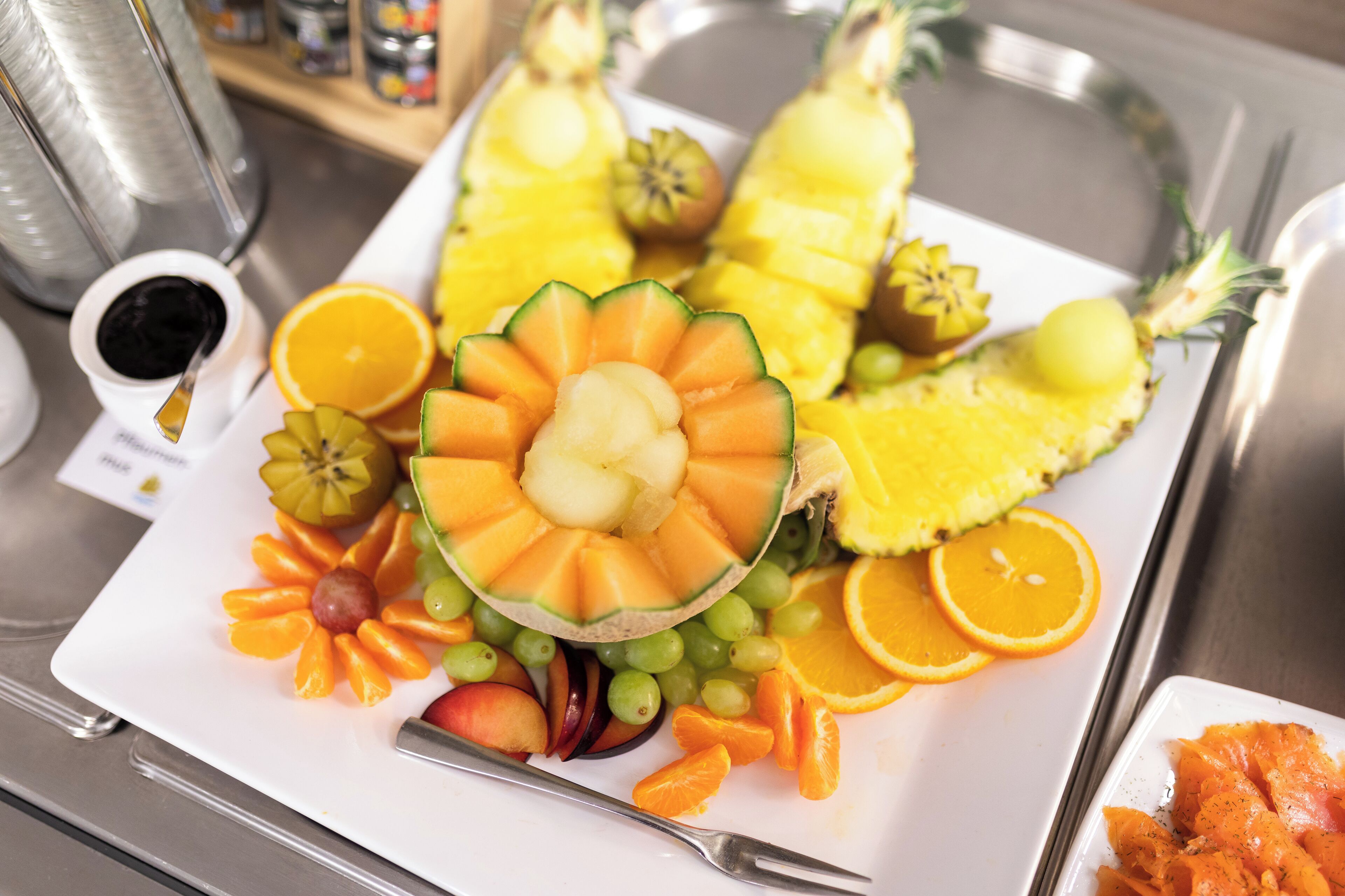Un vassoio con un piatto di frutta assortita e una piccola ciotola di salsa.
