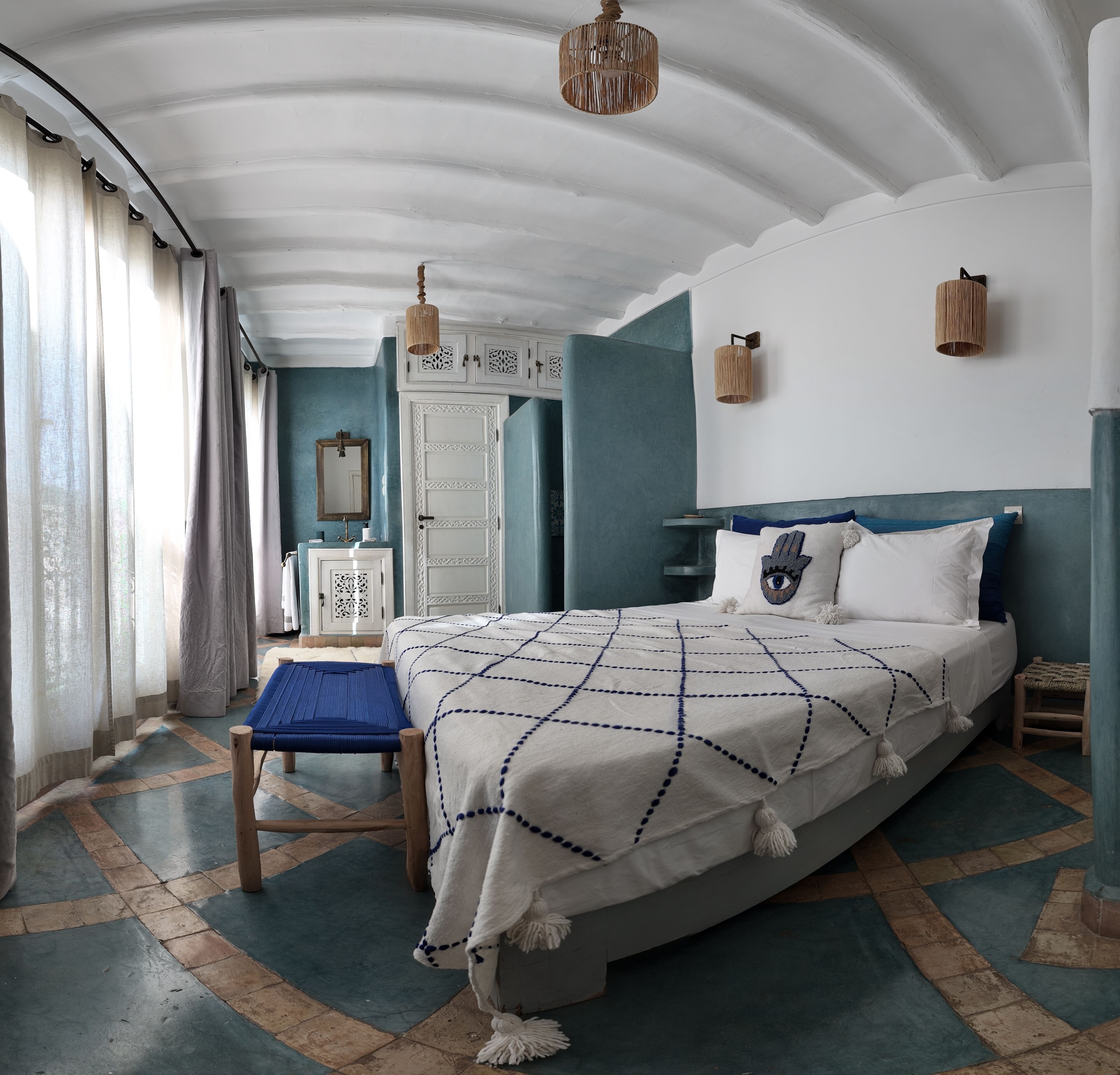 Ein Schlafzimmer mit einem großen Bett, einer hölzernen Bank, einem Kleiderschrank und einem Spiegel.