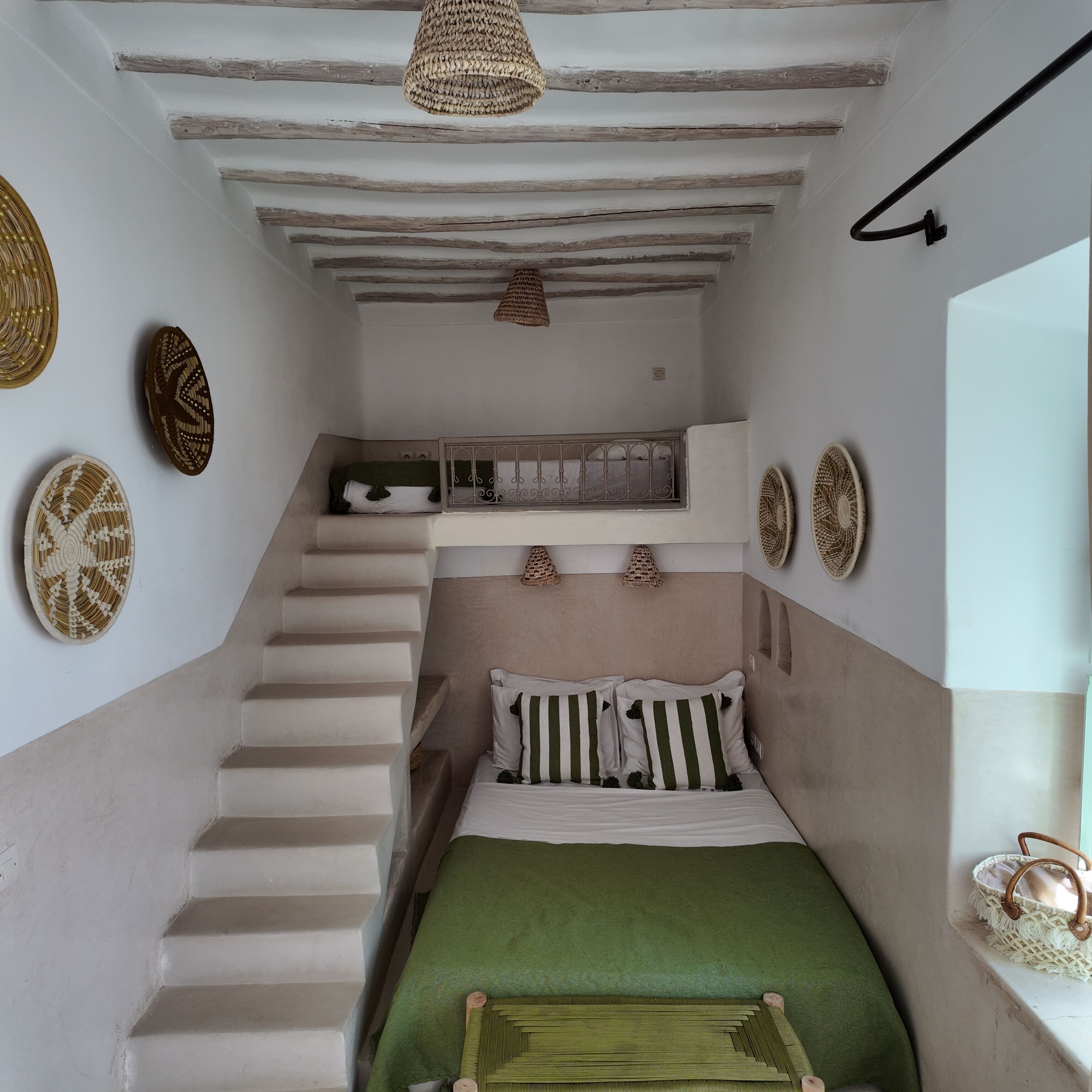 Ein kleines Schlafzimmer mit Bett, einem Fenster und einer Treppe.