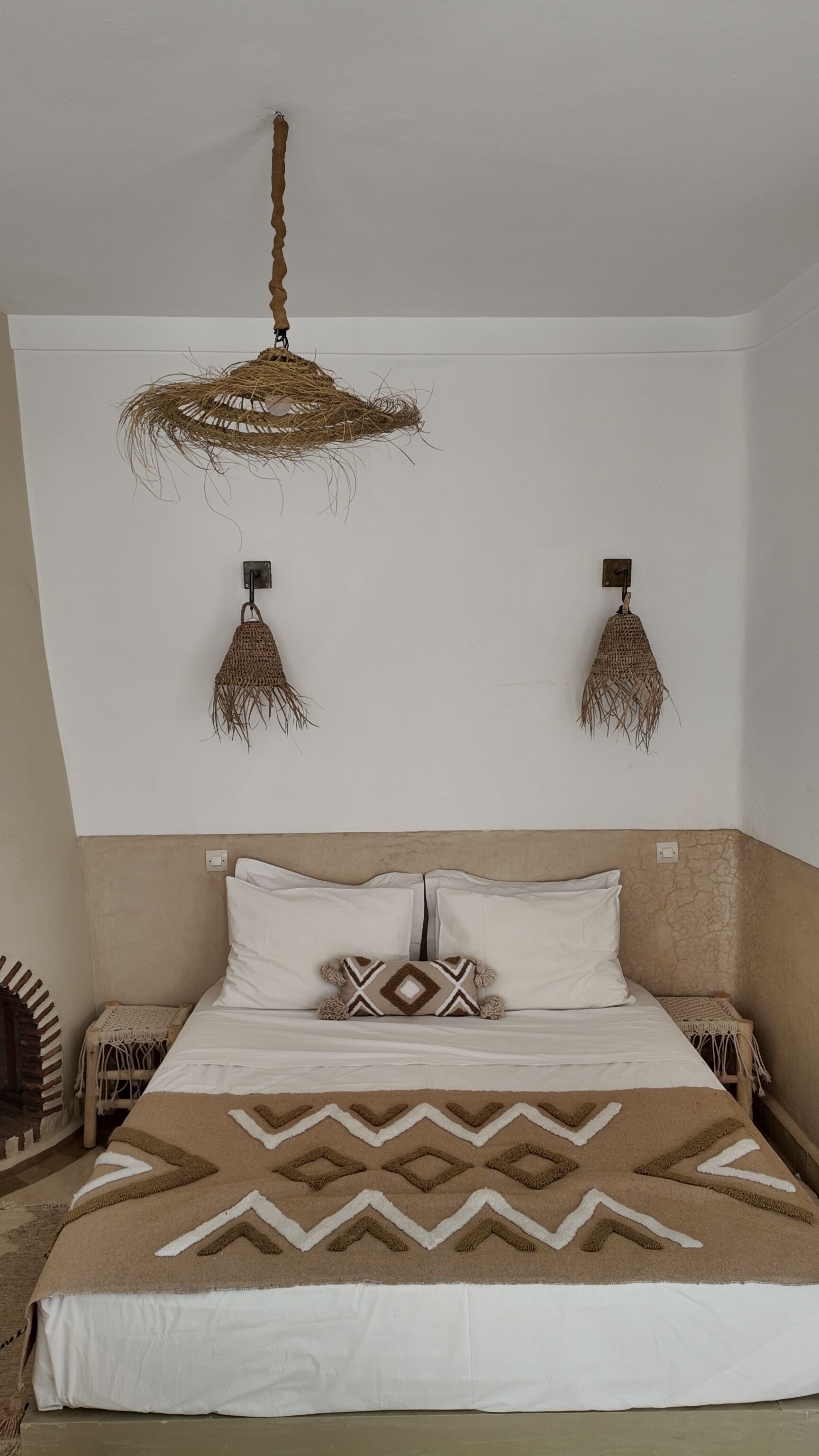 A bedroom with a bed, a hanging light fixture, and two wall-mounted lamps.
