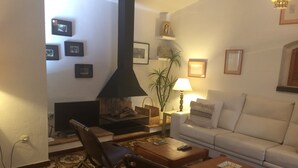 Een woonkamer met een open haard, een bank, een salontafel en een televisie.