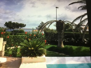A garden with a pool, palm trees, and a view of the sea. - House with pool near the beach and marina (Cala en Bosc)