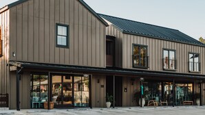 A modern building with a large glass storefront and a metal roof. - Gaines Ranch on the Square | 5 Private Suites | Sleeps 18 (Wimberley)