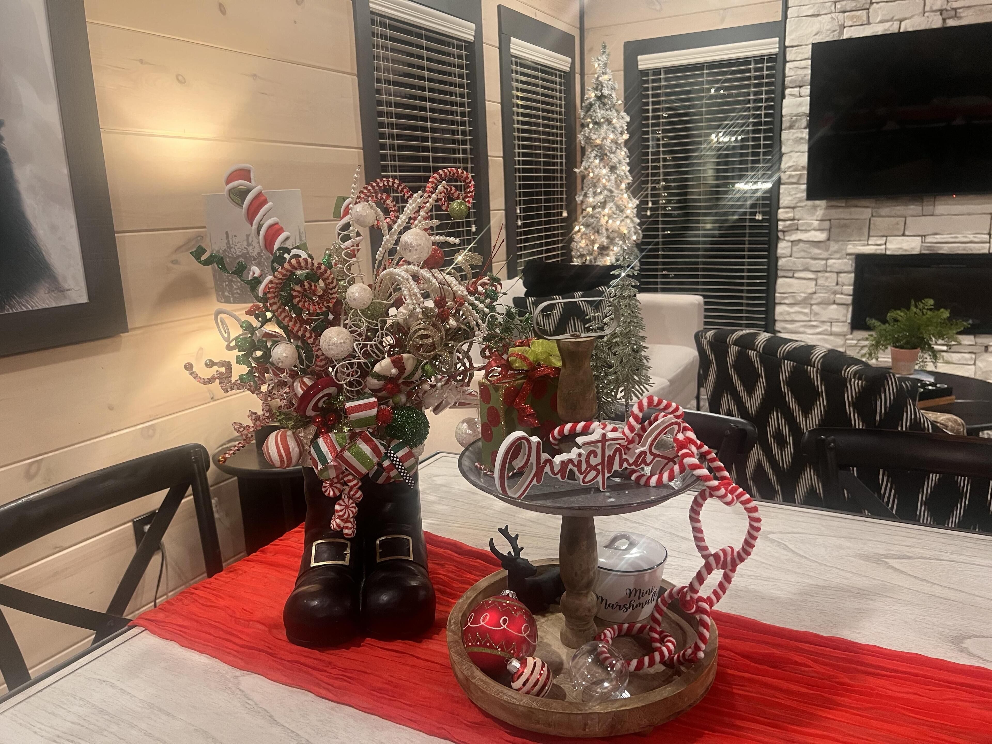 A dining area with a red tablecloth, a Christmas tree, and a festive centerpiece.
