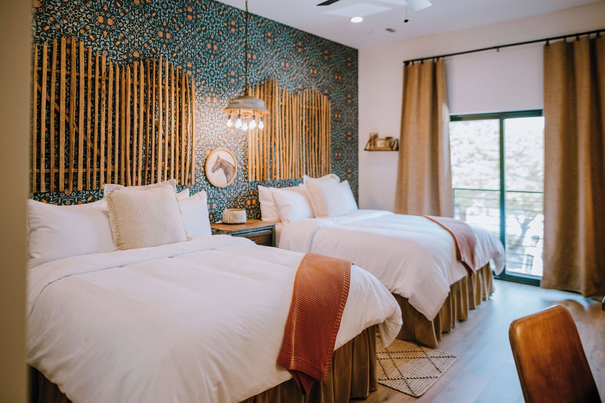 Two queen beds with pillow-top mattresses and premium Comphy linens at the Corral Suite — a modern Western suite at Gaines Ranch on the Square that sleeps four.