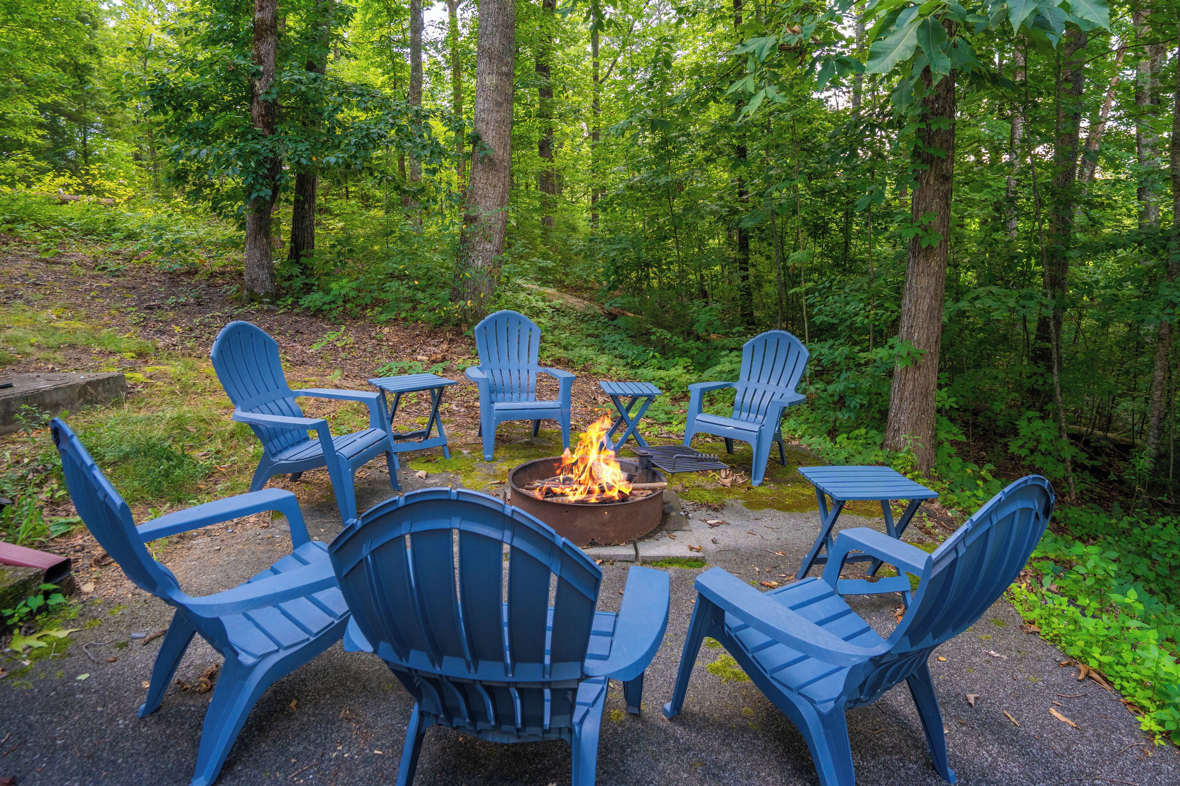 A circular seating arrangement around a central fire pit in a forested area.