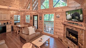 Una cabaña con interior de madera, chimenea, televisor y comedor.