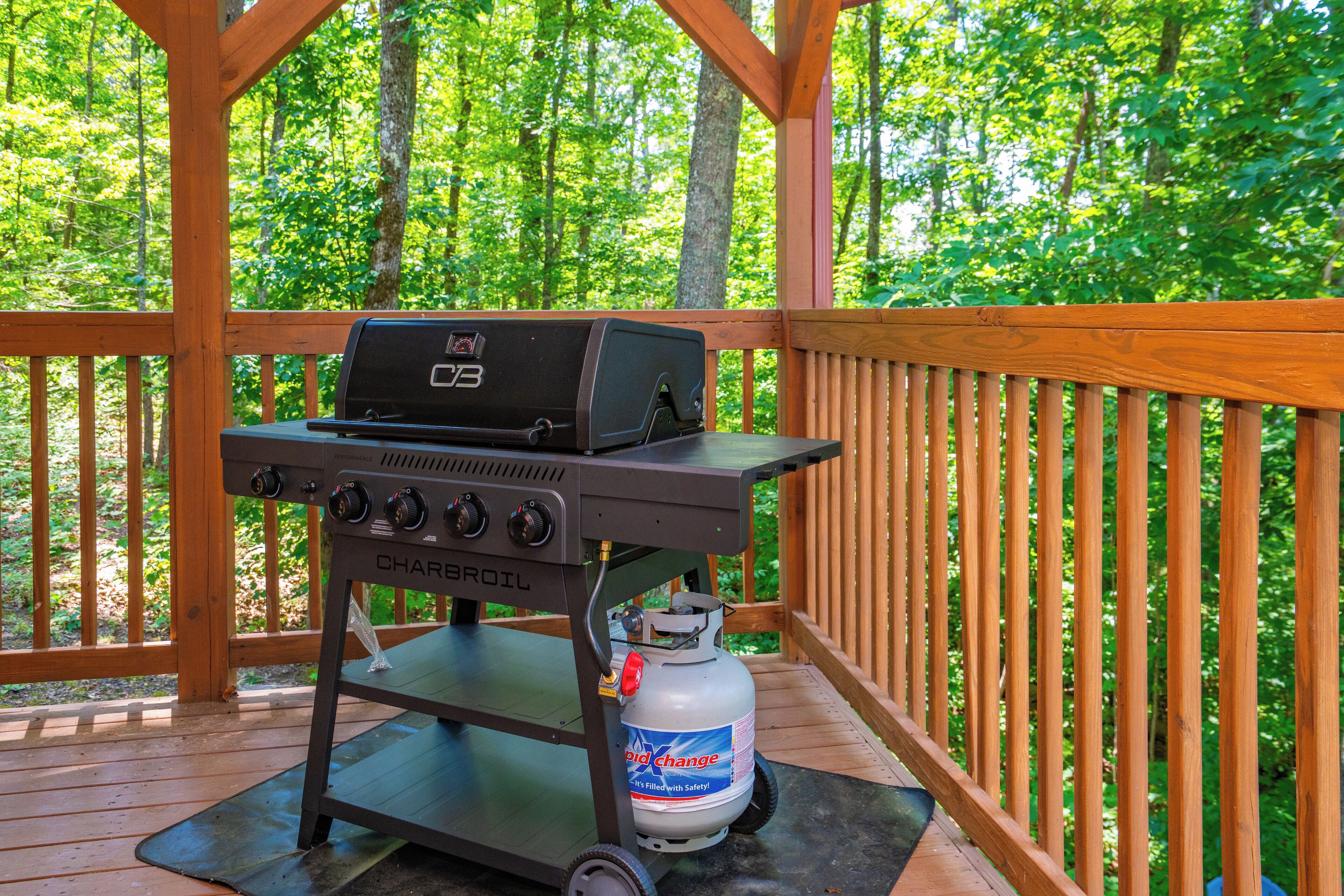A portable barbecue grill with a propane tank on a wooden deck.