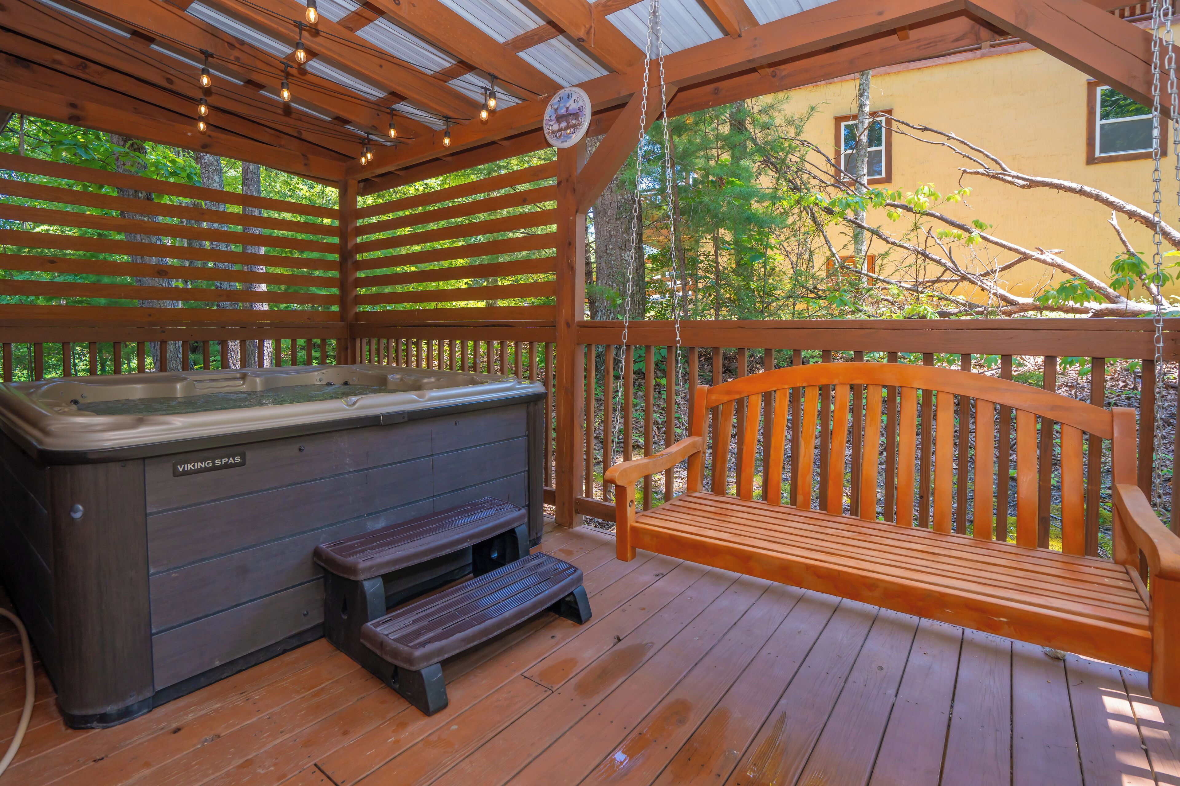 Een houten terras met een jacuzzi en een houten bankje.