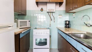 A kitchen with wooden cabinets, a white stove, a microwave, and a sink.