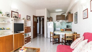 A compact living space with a kitchenette, a dining area, and a seating area with a red sofa.