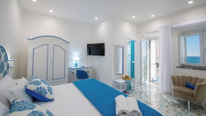 Ein Hotelzimmer mit Bett, Schreibtisch, Stuhl, Fernseher und Meerblick.