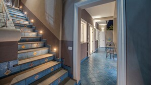 Eine Treppe mit dekorativen Fliesen, ein Korridor mit Türen und ein kleiner Tisch mit Stühlen.